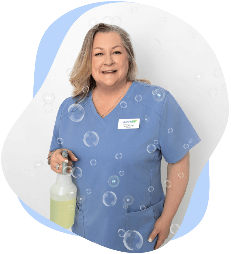 Owner, Angela holding a spray bottle and smiling.